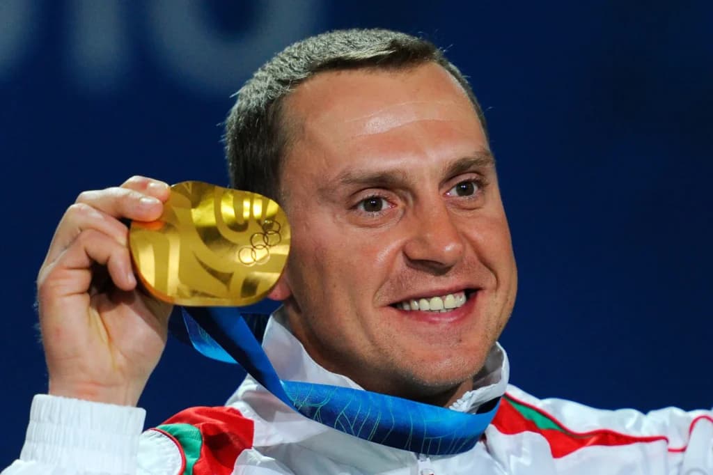 Athlete holding a Vancouver 2010 gold medal, showcasing its unique curved design and golden finish.