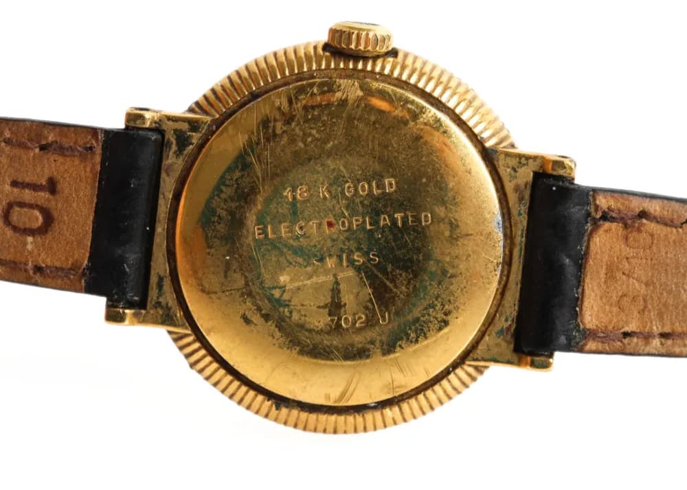Close-up of an 18k gold plated hallmark on the back of a vintage wristwatch, showing a typical gold plated hallmark with the word “electroplated."