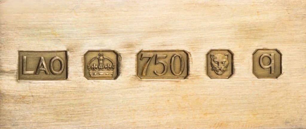 Close-up of an 18ct gold hallmark featuring a 750 stamp alongside traditional UK hallmark symbols.