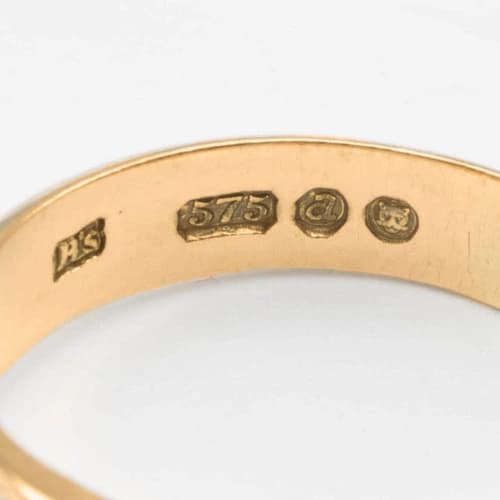 Close-up of a 575 hallmark on gold ring, indicating 14ct gold with 57.5% purity.