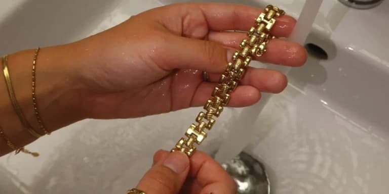 A person rinsing a gold-plated chain bracelet under a tap as part of the gentle cleaning process. After soaking in mild soapy water, gold plated jewellery should be thoroughly rinsed and dried to prevent any soap or water residue from causing tarnish.