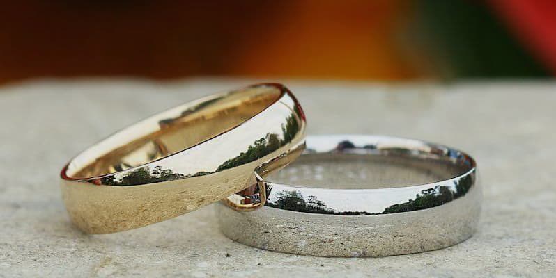 Gold vs platinum wedding rings side by side, showing the colour difference between yellow gold and silvery-white platinum.