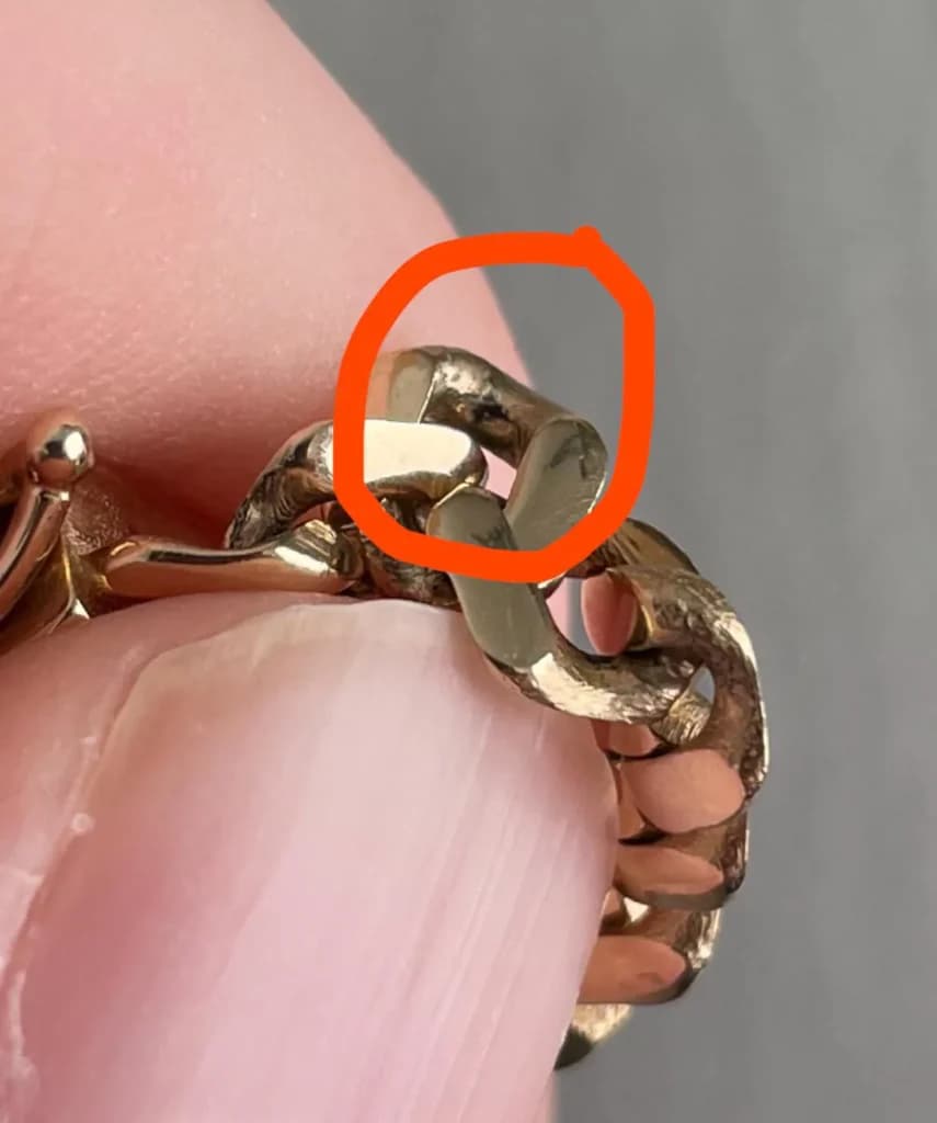 Close-up image showing tarnish on 9ct gold jewellery, highlighting discolouration and wear on a gold bracelet link.