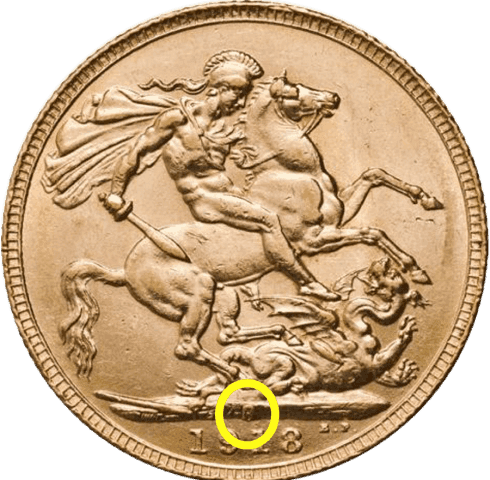 Close-up of a gold coin showing the mint mark on Gold Sovereigns, used to identify the mint location where the coin was produced.