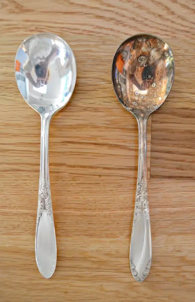 Tarnish on silver shown on a spoon beside a fully cleaned silver spoon for comparison.